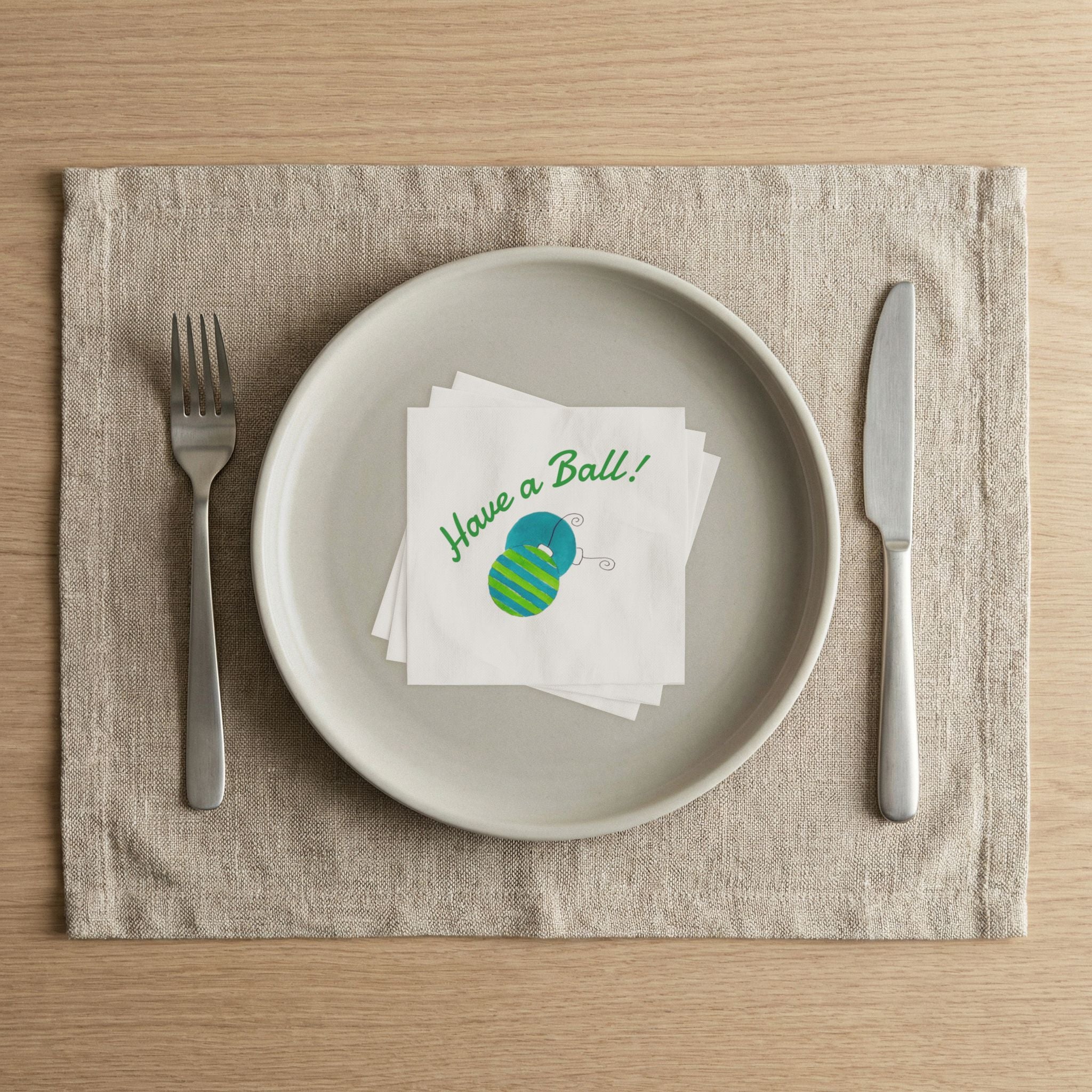 Holiday place setting with Laura Trevey Have a Ball Christmas cocktail napkins on a linen placemat