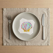 Beach house table place setting with Laura Trevey scallop shell paper napkins on a linen placemat