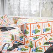 Citrus orange tree wrapping paper with watercolor orange trees in blue and white chinoiserie pots and Coastal Christmas script by Laura Trevey, gift wrap in a holiday wrapping scene