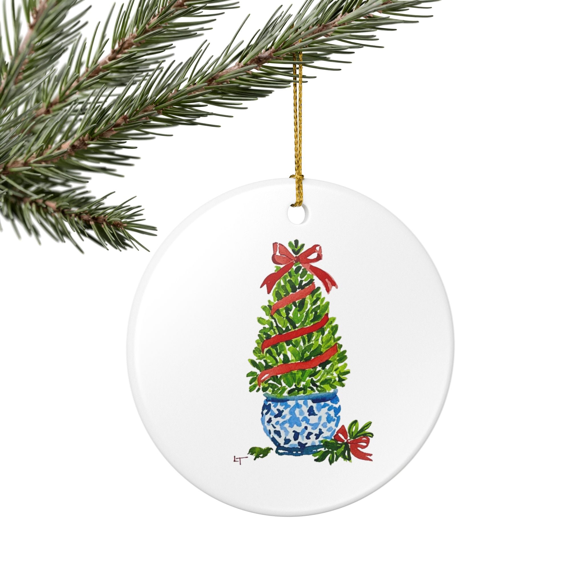 Boxwood topiary chinoiserie ornament hanging from an evergreen branch