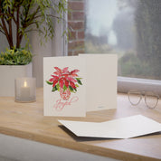 Joyful red poinsettia watercolor holiday card on a windowsill desk with envelope