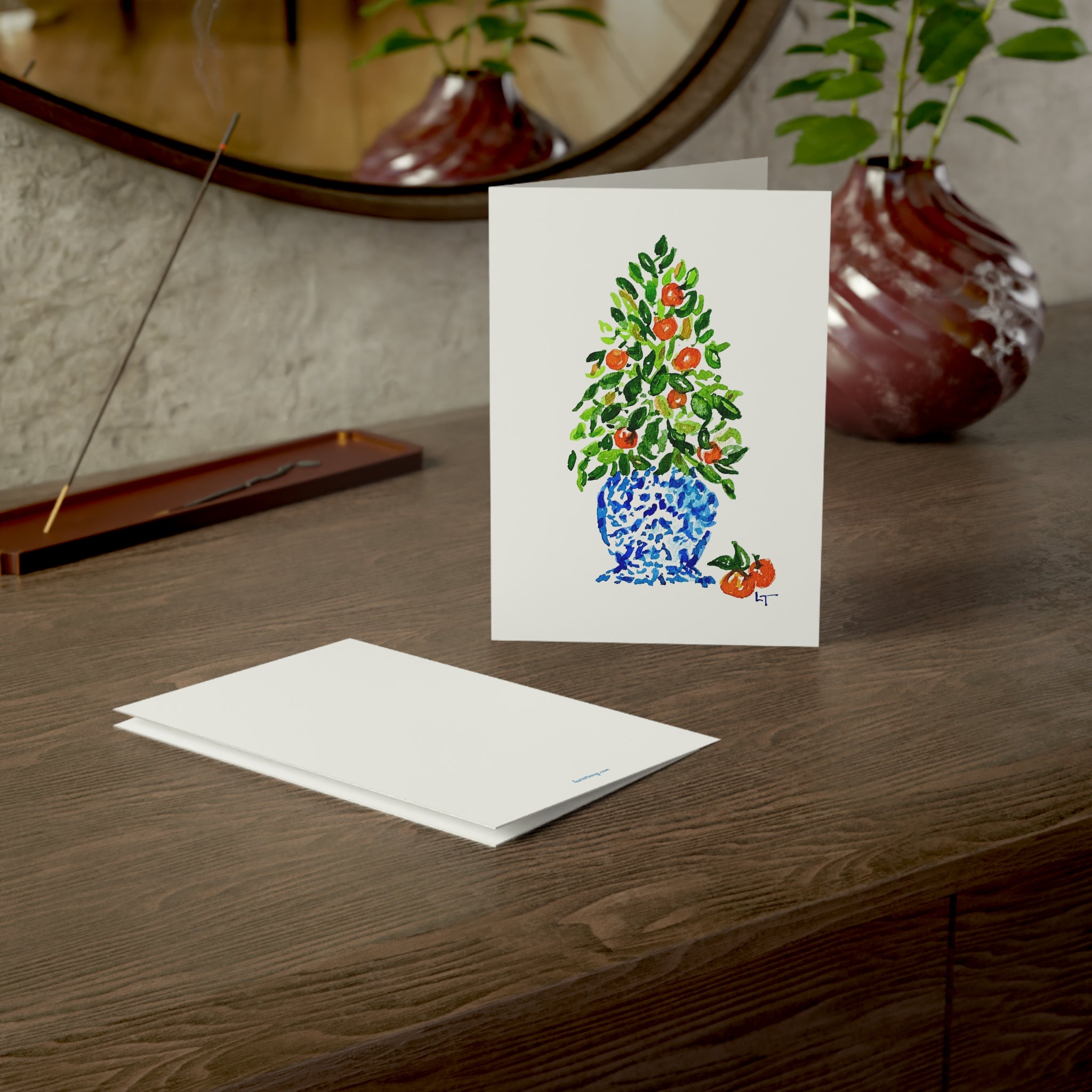 Orange tree Christmas topiary in blue and white chinoiserie pot watercolor Christmas card on a wooden dresser with envelope