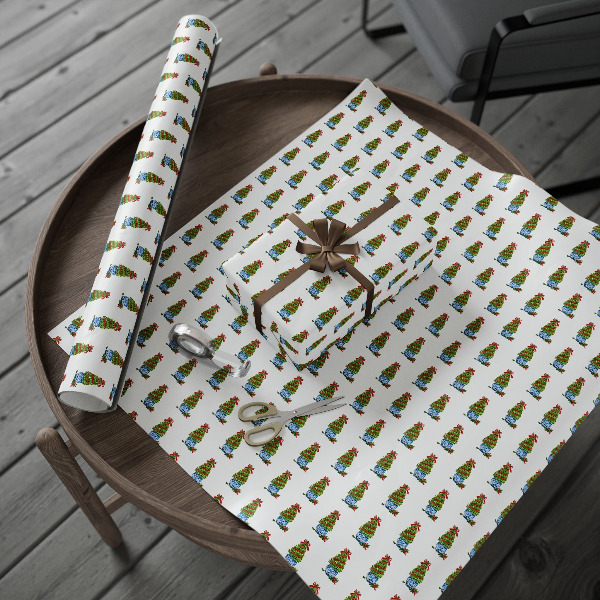 Christmas topiary wrapping paper with watercolor boxwood trees in blue and white chinoiserie pots by Laura Trevey, full sheet with a wrapped gift on a wooden table