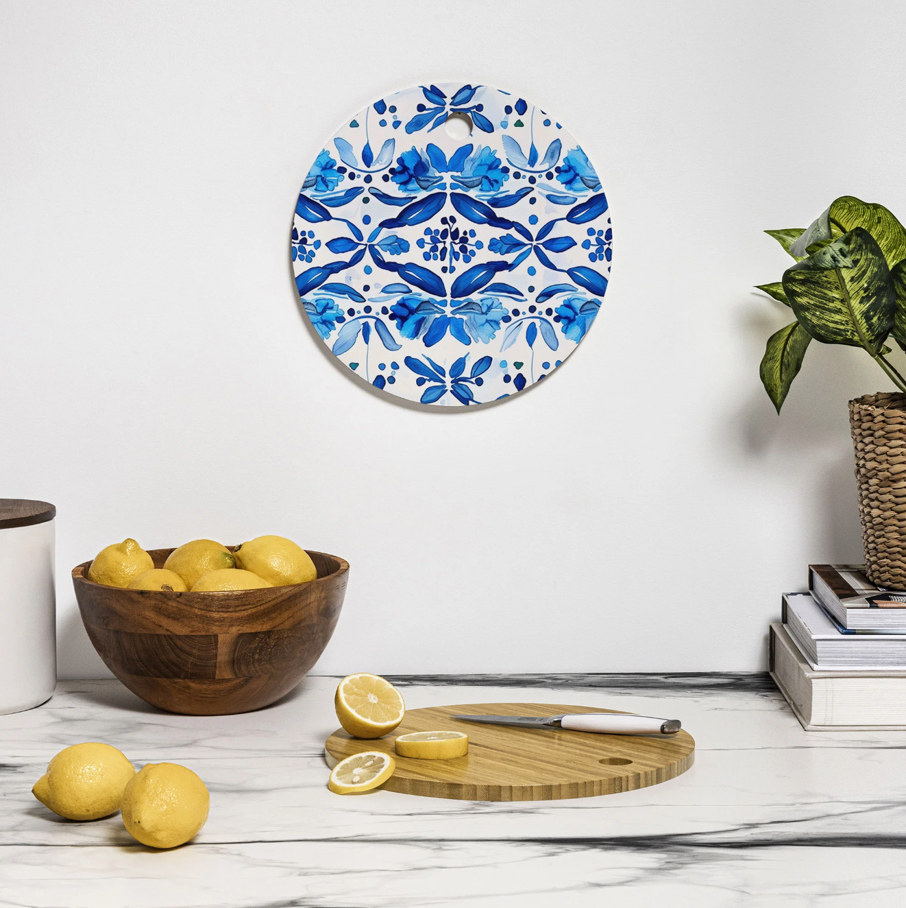 Decorative bamboo cutting board with blue Spanish tile inspired pattern on a kitchen counter.