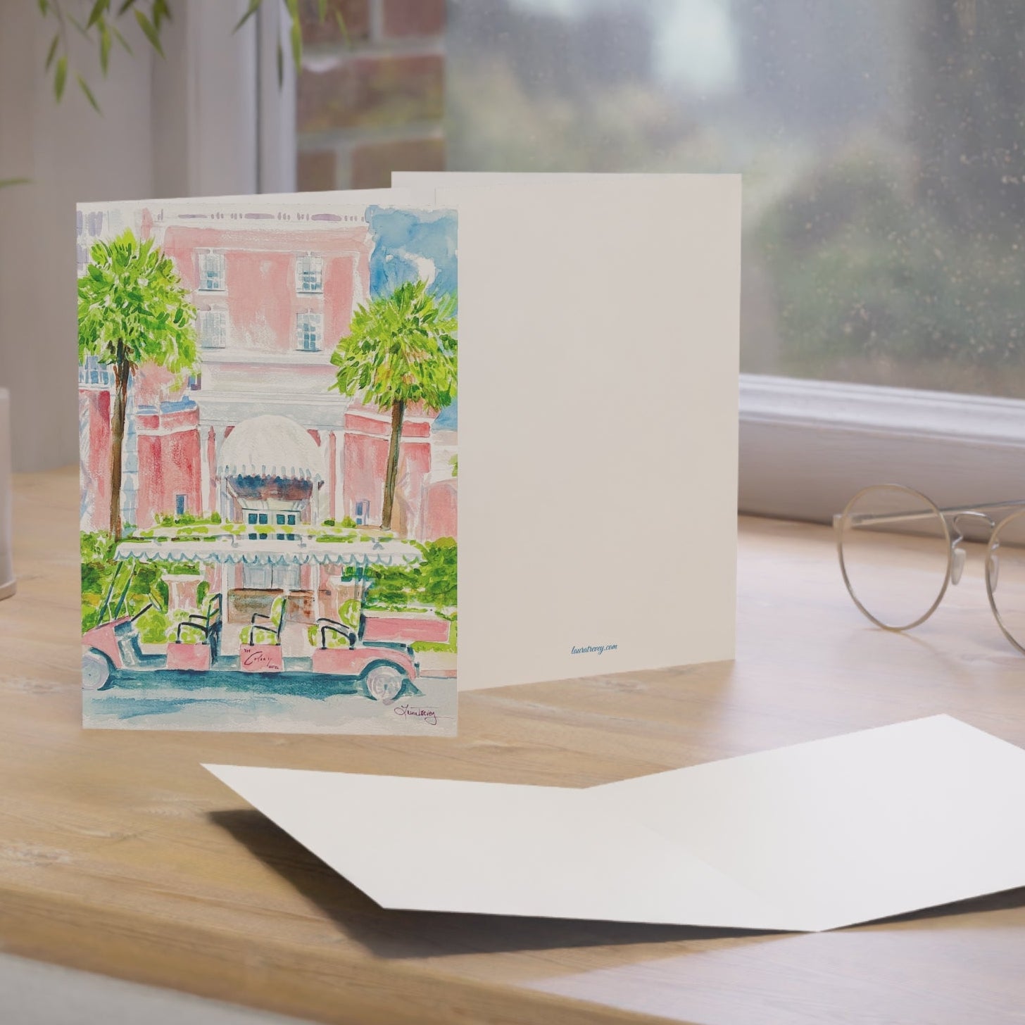 The Colony Hotel watercolor greeting card, standing on a windowsill desk with envelope