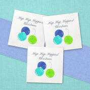 Hap Hap Happiest Christmas Blue Cocktail Napkins | Watercolor Ornament Paper Napkins – paper napkins spread on aqua linen with a periwinkle blue table runner