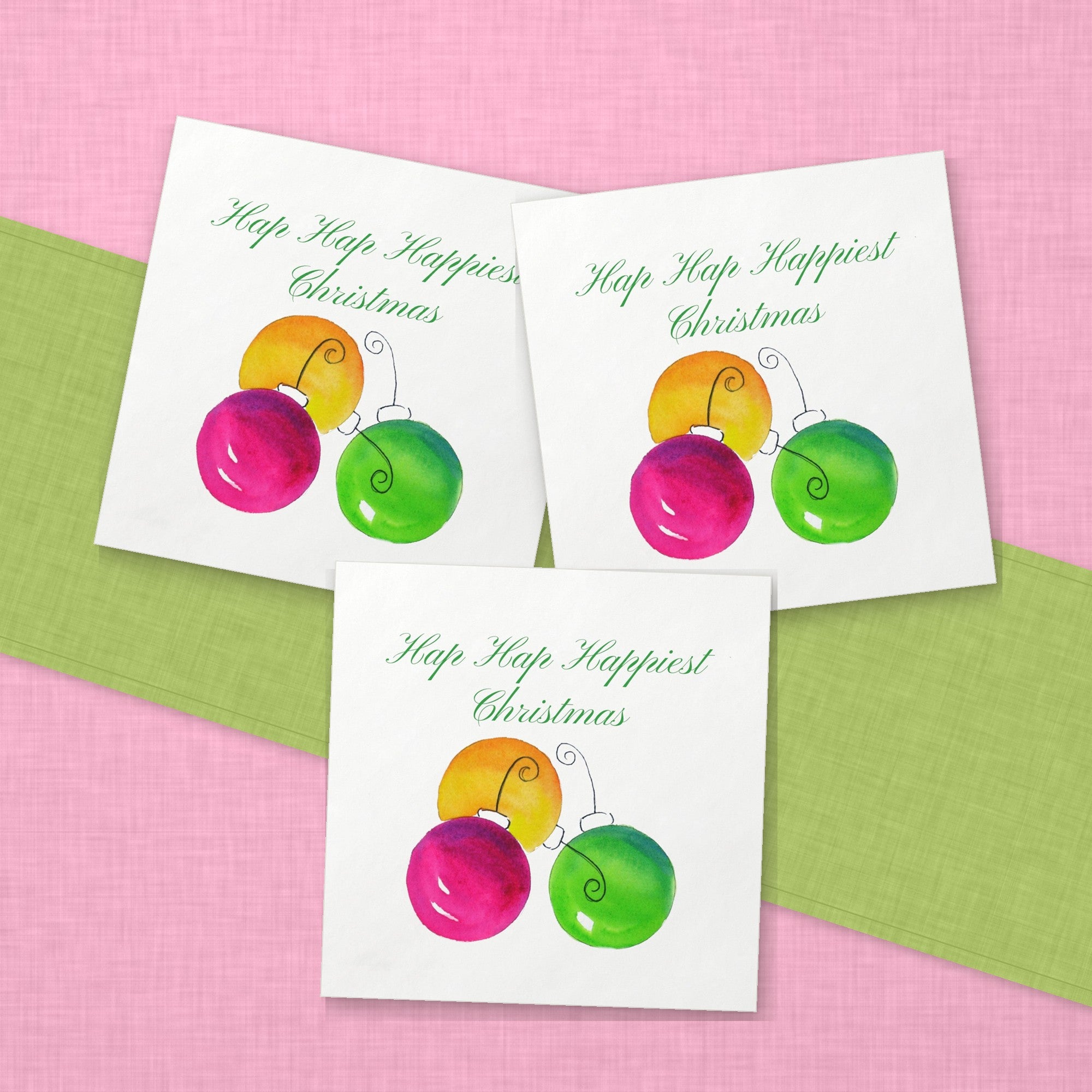Hap Hap Happiest Christmas Cocktail Napkins | Watercolor Ornament Paper Napkins – paper napkins spread on pink linen with a lime green table runner