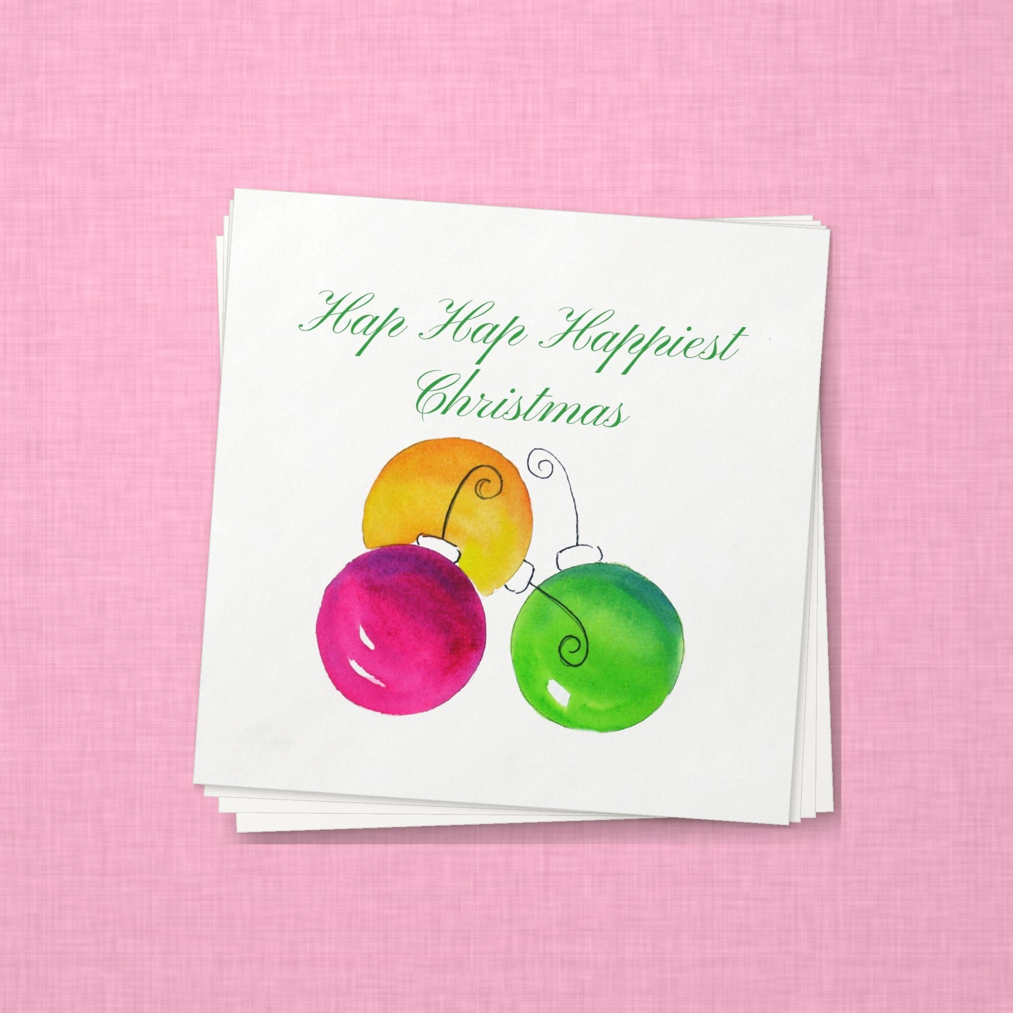 Hap Hap Happiest Christmas Cocktail Napkins | Watercolor Ornament Paper Napkins – stack of cocktail napkins on pink linen