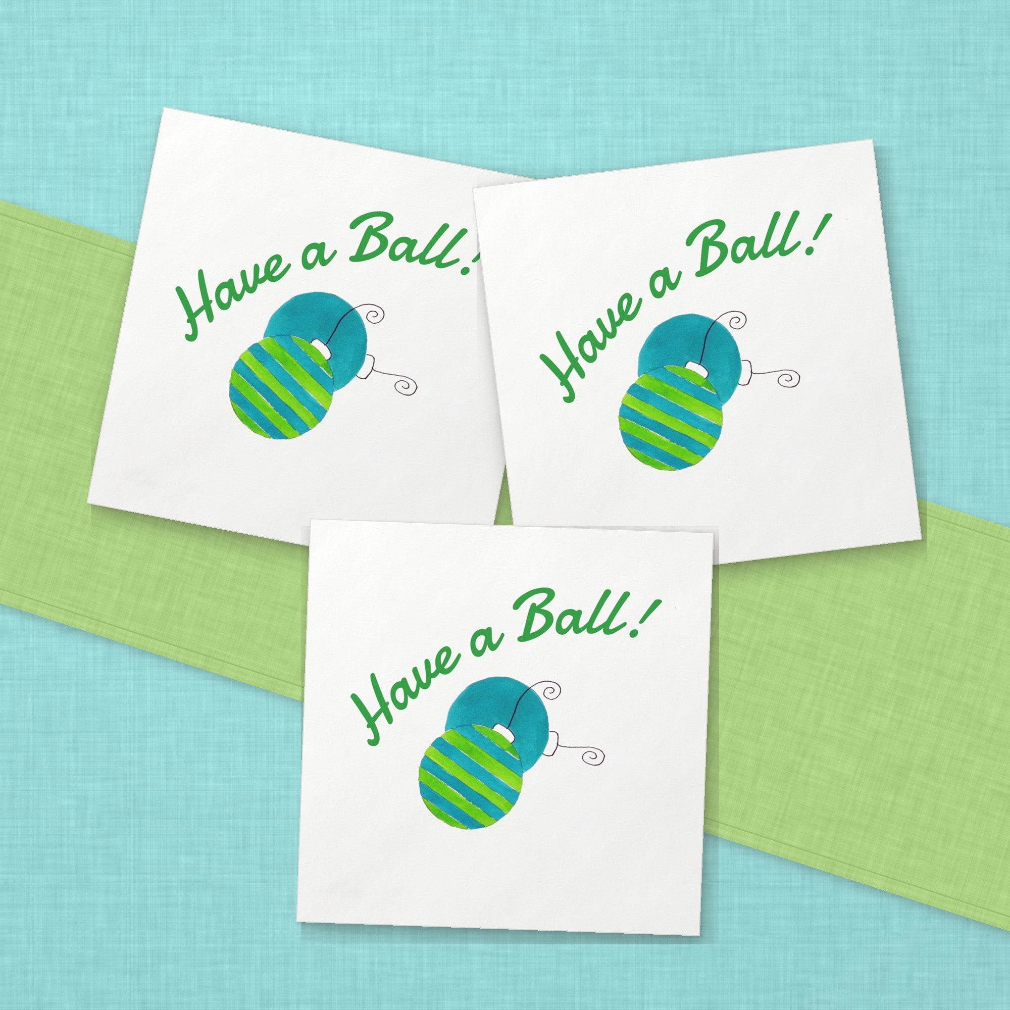 Have a Ball Christmas Cocktail Napkins | Watercolor Ornament Paper Napkins – paper napkins spread on aqua linen with a lime green table runner